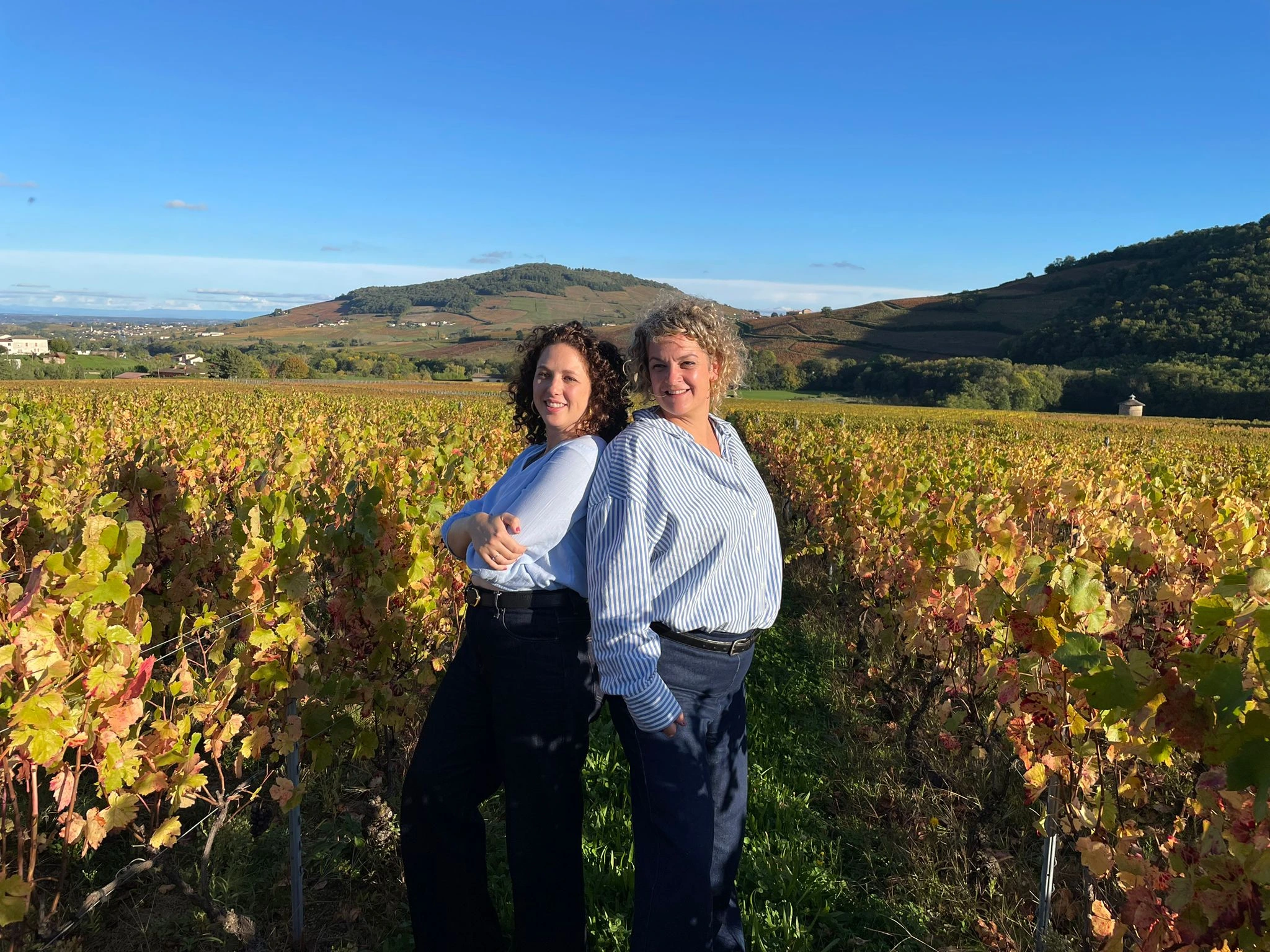 Les deux fondatrices des Epicurieuses,Inès Delmotte et Anaïs Burnichon souriante dans les vignes devant le Mont Brouilly