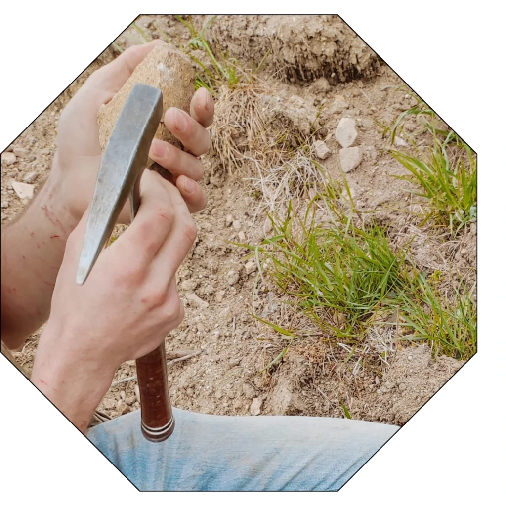 Un géologue archéologue tient une petite pioche et un cailloux fraichement extrait du sol du Beaujolais