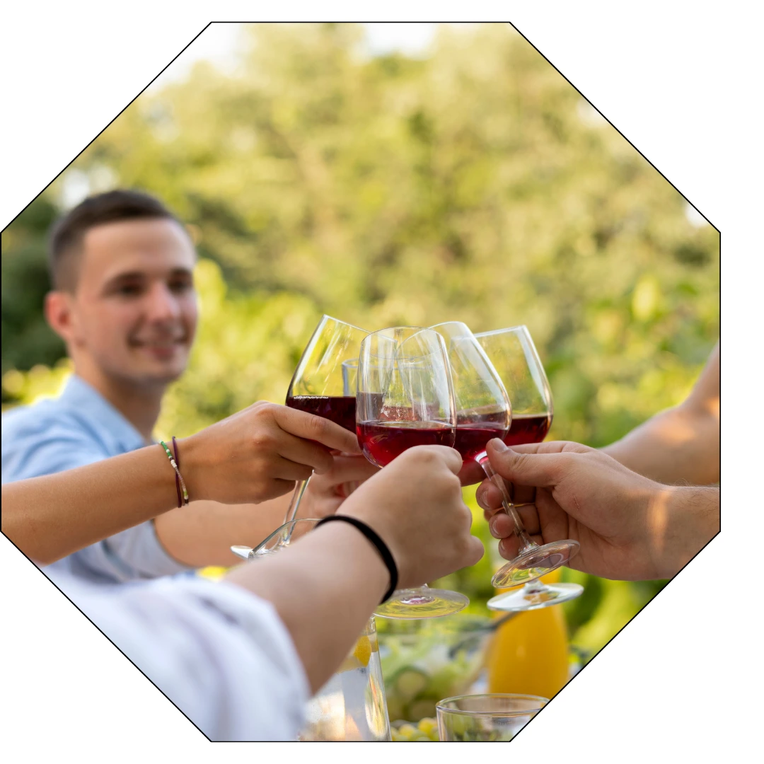 Ambiance conviviale lors de cette dégustation entre cinq personnes qui trinquent sous un ciel bleu avec en arrière plan un homme qui sourit.