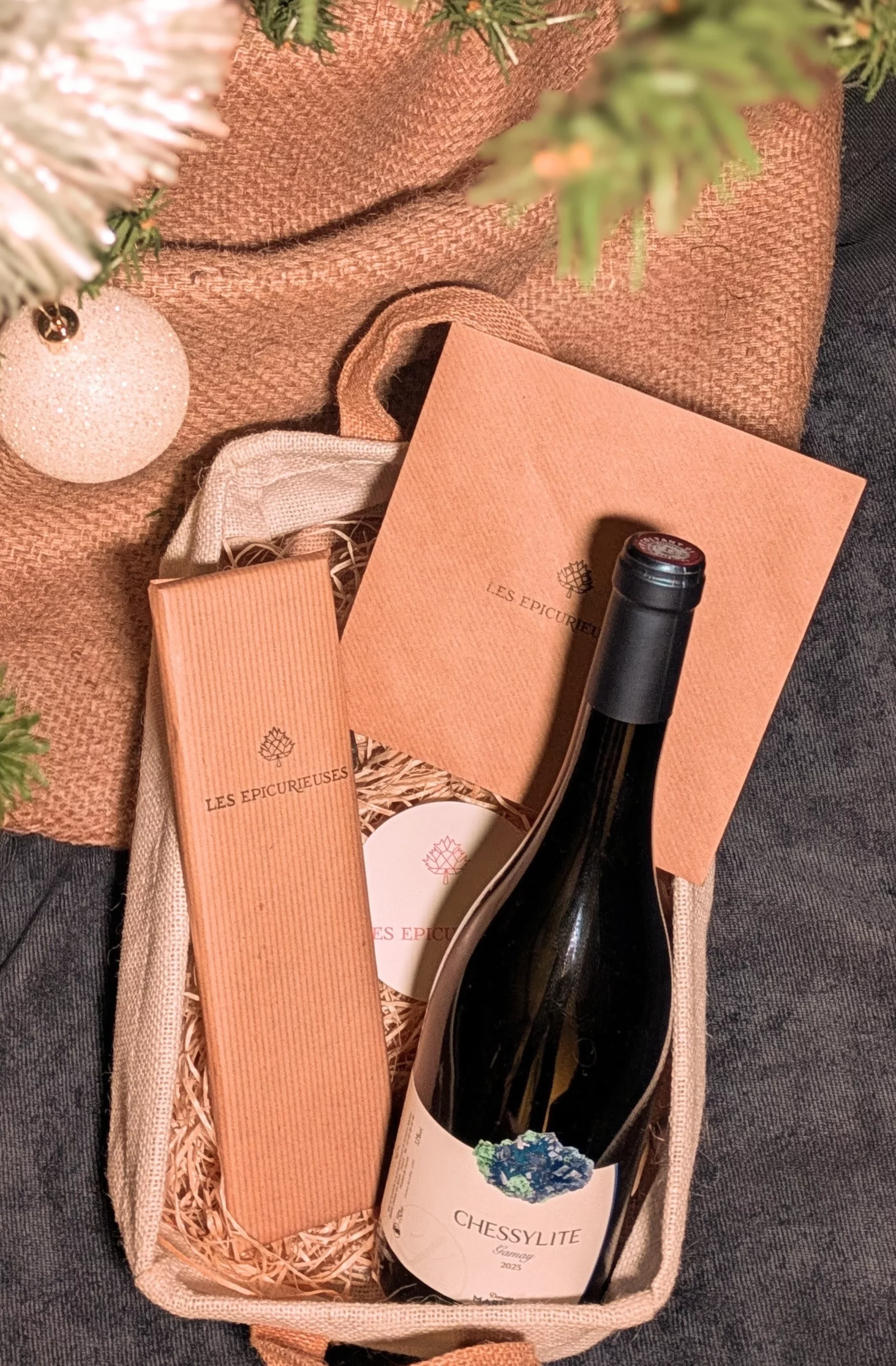 Photo box gourmandises : un voyage immersif by Les Epicurieuses : idée cadeau noël. Contient un bon cadeau pour une expérience oenologique, une bouteille de beaujolais rouge et une tablette de chocolat origine équateur R